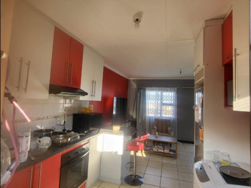 Open-plan kitchen and living area featuring modern two-tone cabinetry, built-in oven, extractor fan, and tiled flooring throughout.