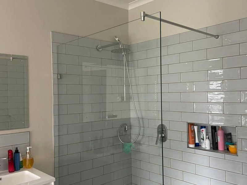 Modern bathroom featuring a walk-in shower with glass screen, subway tiling, built-in shower niche, and a contemporary vanity basin.