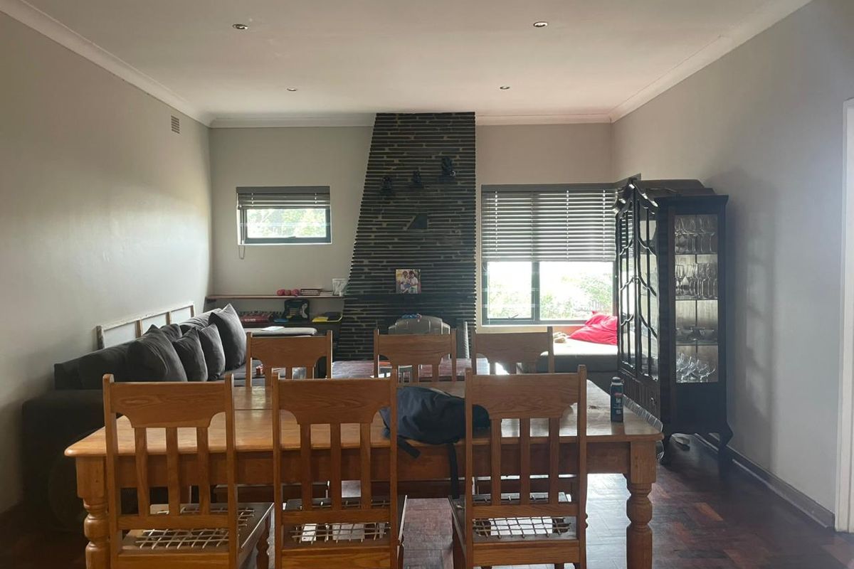 Spacious living and dining area featuring a prominent brick fireplace, parquet flooring, and recessed lighting, offering a comfortable and functional layout.