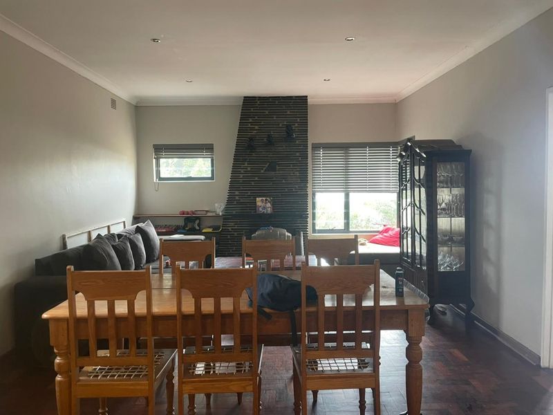 Spacious living and dining area featuring a prominent brick fireplace, parquet flooring, and recessed lighting, offering a comfortable and functional layout.