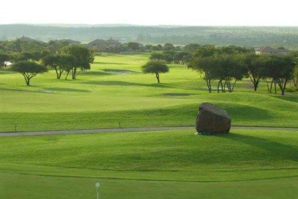 A scenic view overlooking a well-maintained golf course with lush green fairways and mature trees.