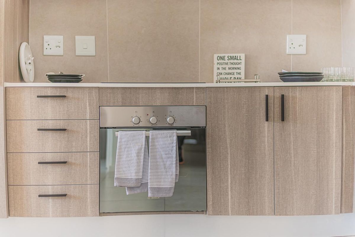 Modern kitchen featuring light wood-grain cabinetry, stone countertops, a tiled backsplash, and a built-in Bosch oven with integrated hob.