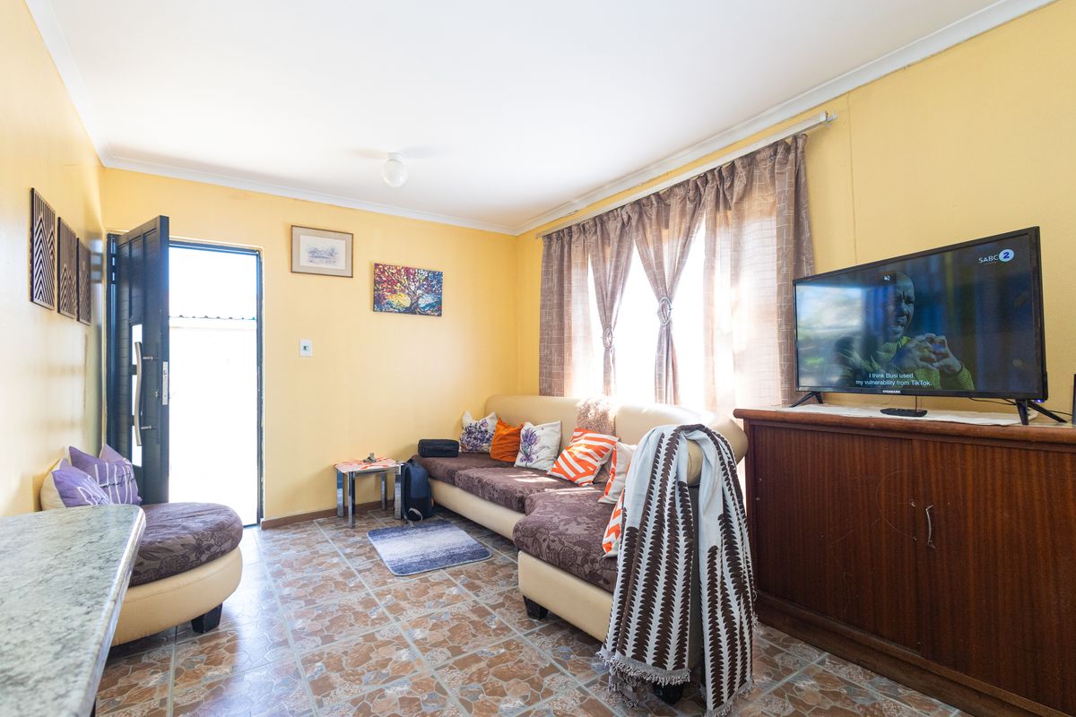 A cozy living room featuring tiled flooring and natural light through large windows, providing a comfortable space for relaxation.