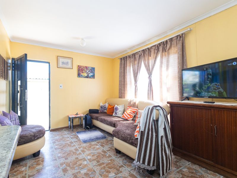 A cozy living room featuring tiled flooring and natural light through large windows, providing a comfortable space for relaxation.