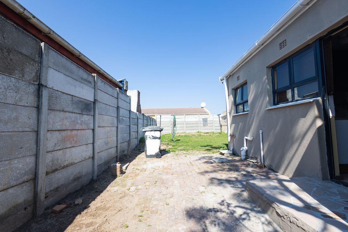 Rear exterior area featuring a brick paved patio, precast concrete boundary walls, and a small grassed section.