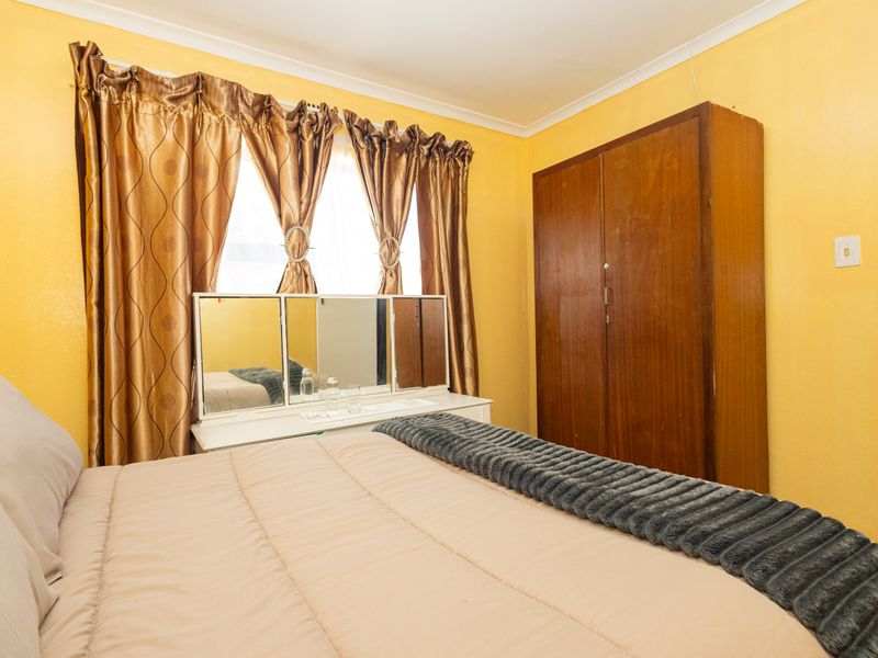 A bedroom featuring a built-in wardrobe and coving, finished with yellow wall paint.