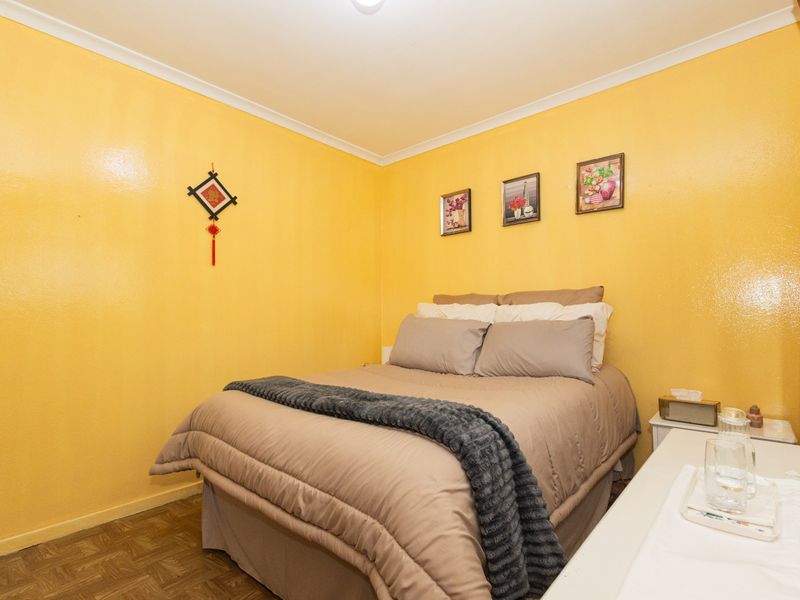 A cozy bedroom featuring parquet flooring and bright yellow walls, providing a warm and inviting atmosphere.
