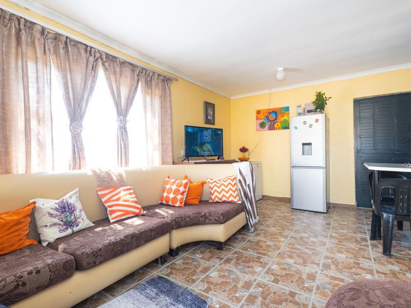 A living area featuring tiled flooring and coved ceilings, offering a functional space with potential for cosmetic updates to enhance the interior aesthetic.