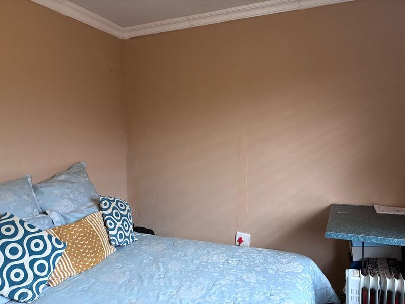 A bedroom corner featuring crown molding and visible wall surface imperfections, requiring cosmetic attention.