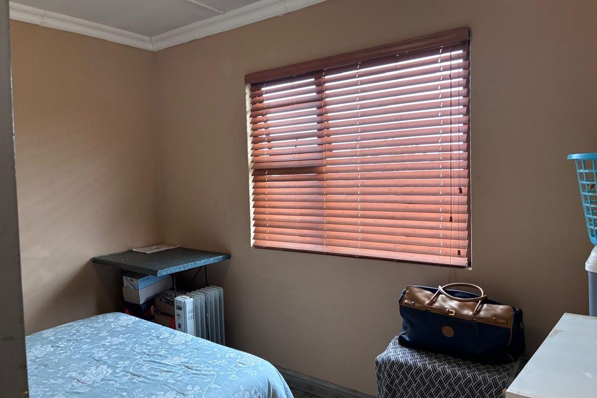 A standard bedroom featuring laminate flooring, coving, and wooden venetian blinds, providing a functional and neutral space.
