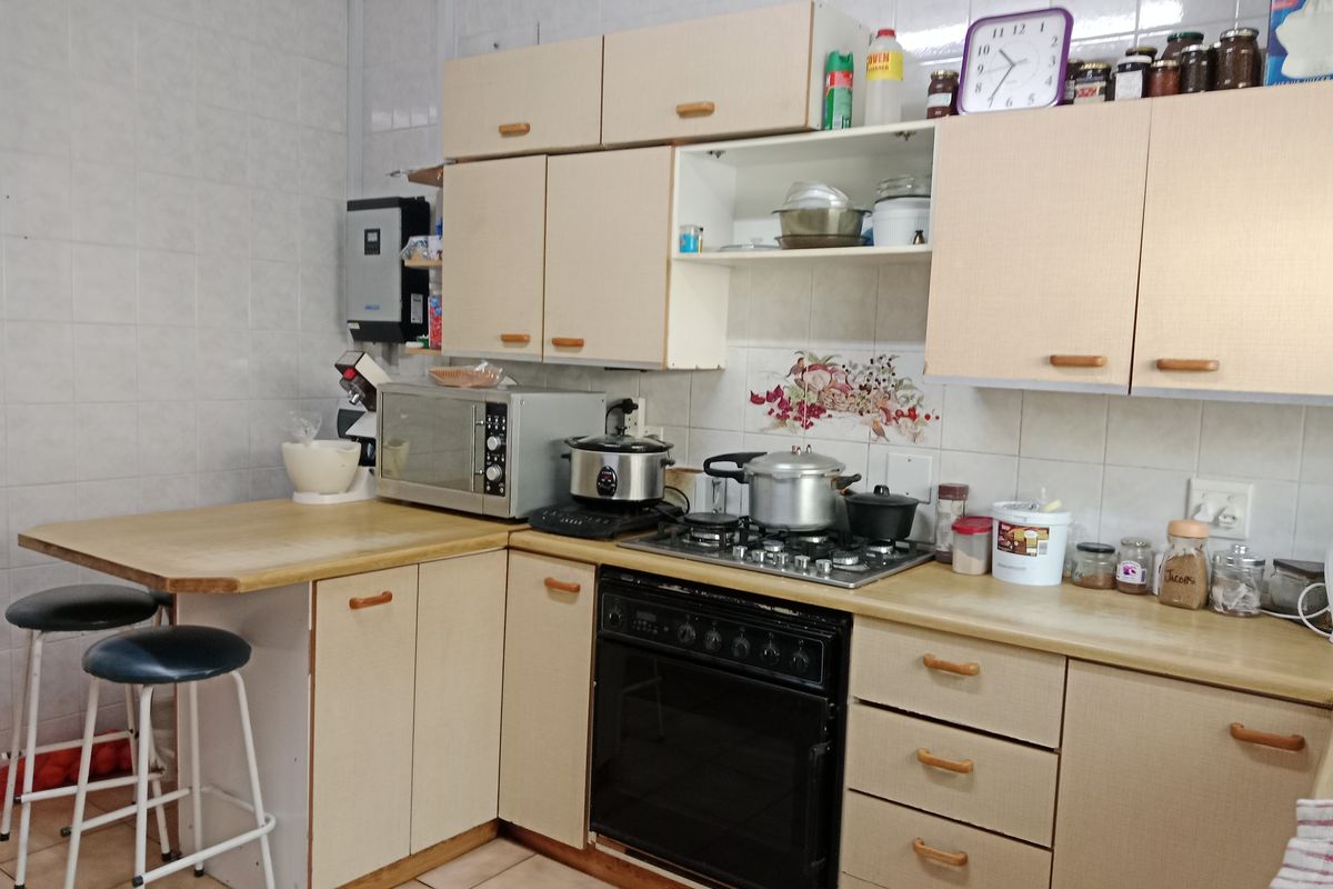 A functional kitchen featuring laminate countertops, built-in cabinetry, a gas hob, and an integrated oven with tiled splashbacks and flooring.