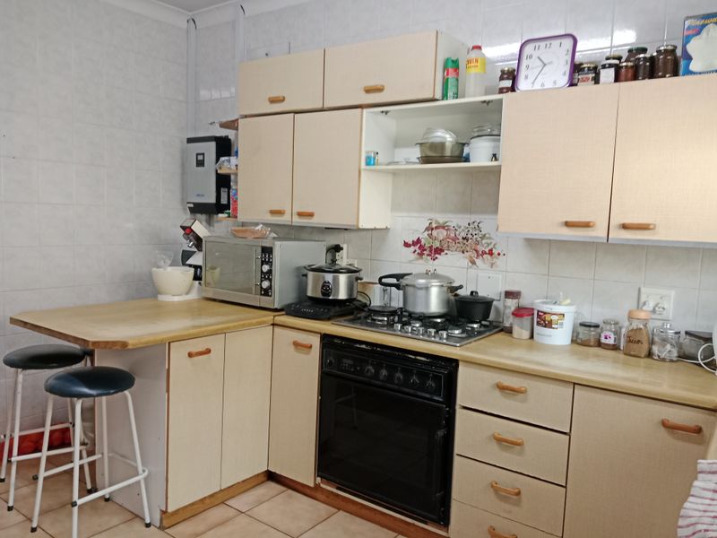 A functional kitchen featuring laminate countertops, built-in cabinetry, a gas hob, and an integrated oven with tiled splashbacks and flooring.