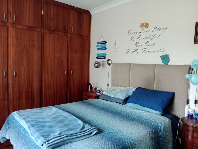 A bedroom featuring extensive built-in wooden cabinetry and wall-mounted lighting fixtures.