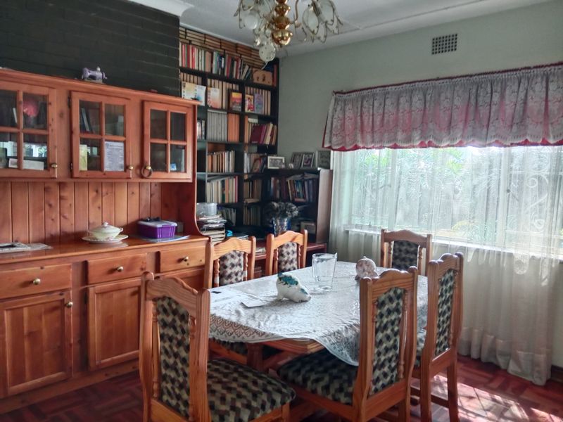 A traditional dining room featuring parquet flooring, a built-in floor-to-ceiling bookshelf, and a brick fireplace surround, offering a classic and functional layout.