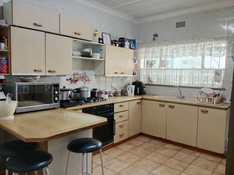 A functional kitchen featuring laminate cabinetry, a built-in oven with gas hob, tiled backsplash, and a breakfast nook area.