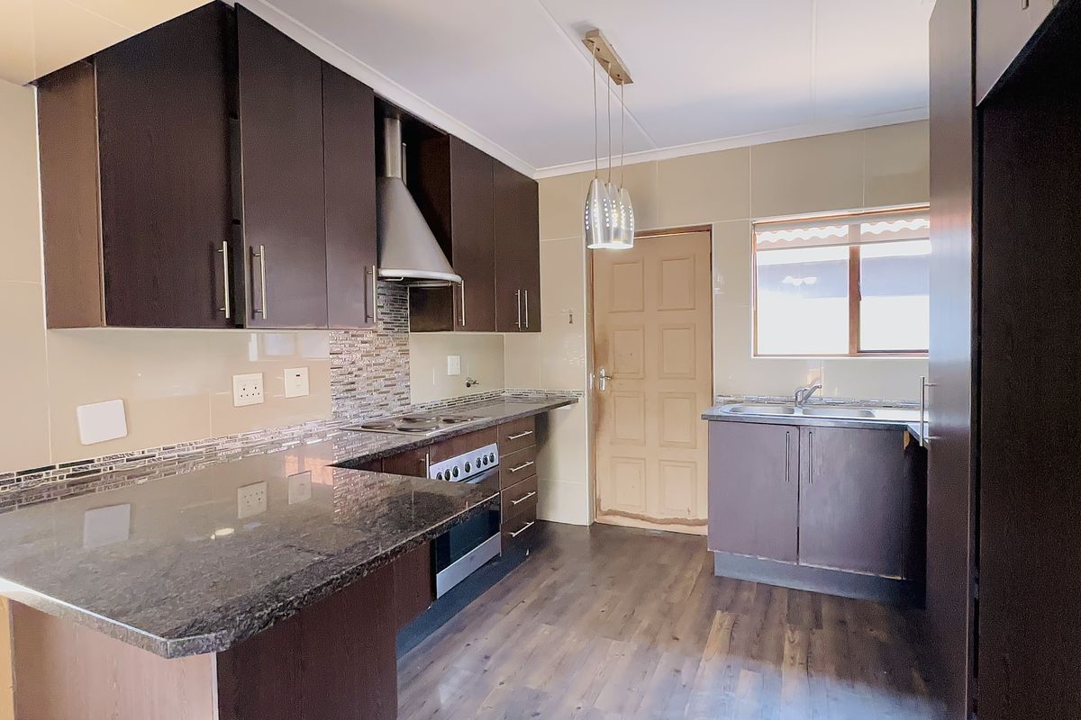 A functional kitchen featuring dark cabinetry, granite countertops, built-in oven with extractor fan, and tiled backsplash, offering a clean and practical workspace.