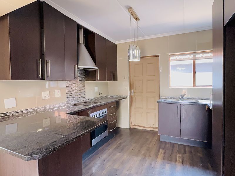 A functional kitchen featuring dark cabinetry, granite countertops, built-in oven with extractor fan, and tiled backsplash, offering a clean and practical workspace.
