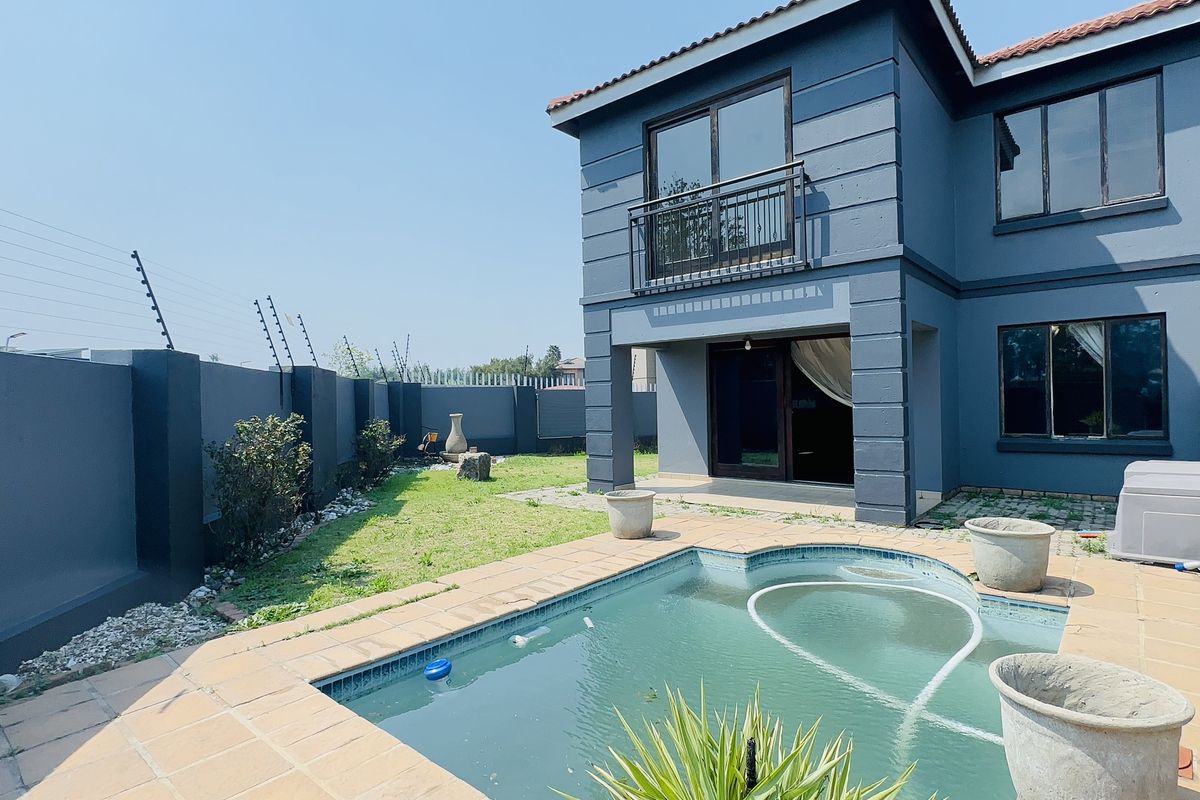 Rear view of a two-story townhouse featuring a private swimming pool, a small garden, and a balcony accessible from the upper level.