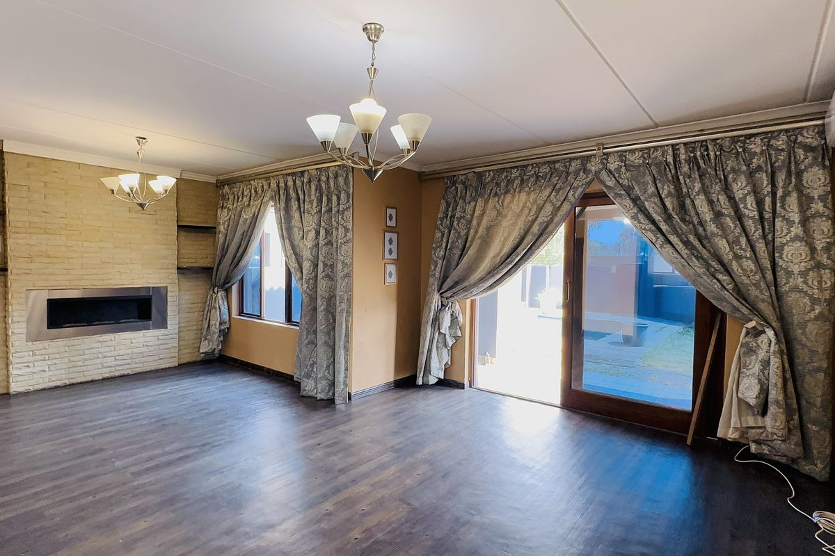 Spacious living room featuring a built-in fireplace with a brick surround, laminate flooring, and direct access to the outdoor area via sliding glass doors.