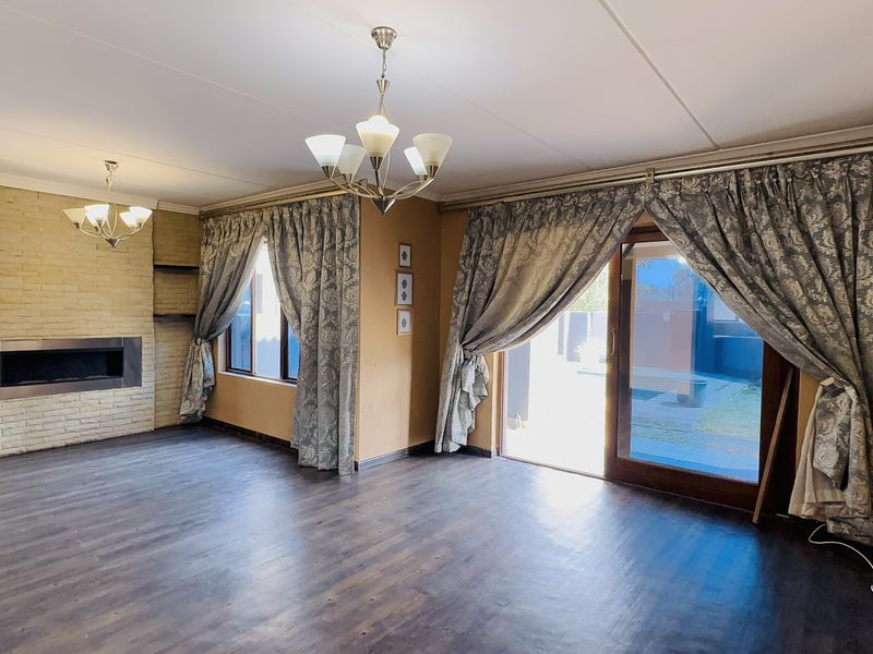 Spacious living room featuring a built-in fireplace with a brick surround, laminate flooring, and direct access to the outdoor area via sliding glass doors.
