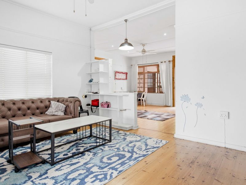 An open-plan living area featuring polished hardwood floors, neutral walls, and a built-in partition shelf, creating a bright and connected living space.