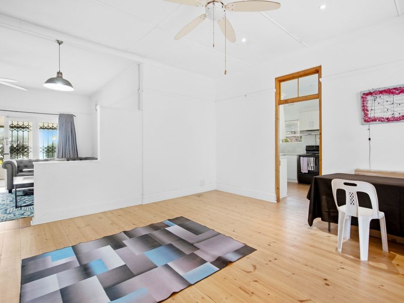 Open plan living area featuring polished timber flooring, ceiling fans, and a direct view into the adjoining kitchen space.