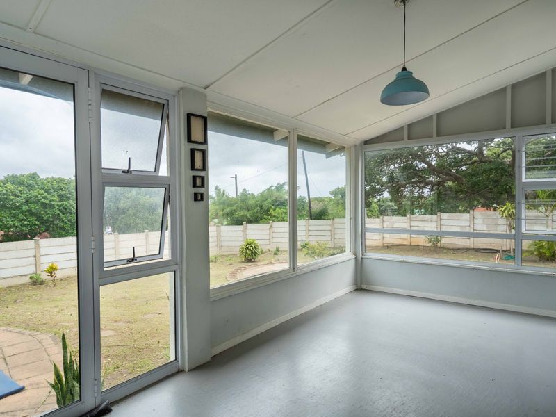 A bright, enclosed patio area featuring large aluminium-framed windows and glass doors, offering views of the rear garden.