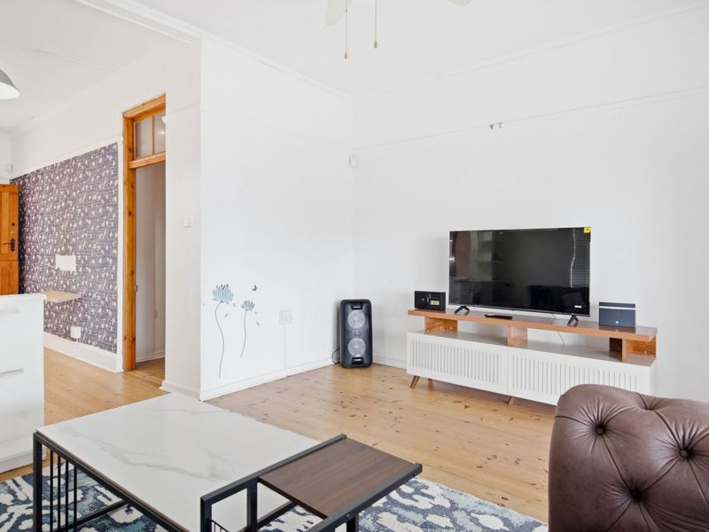 A living room featuring original timber flooring, a ceiling fan, and decorative picture rails, providing a bright and functional space.