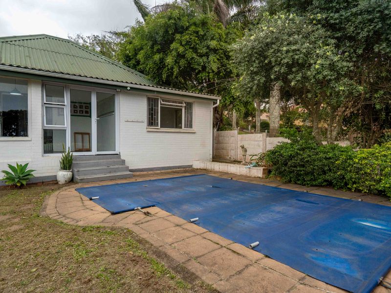 Rear exterior view featuring a swimming pool with a cover, paved patio area, and direct access to the home via glass doors.