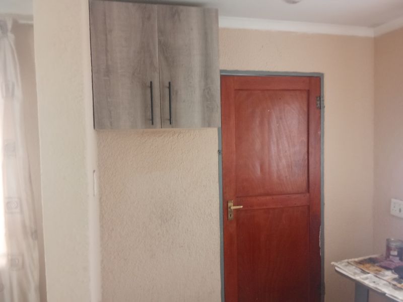 A small interior space featuring a wall-mounted cabinet and a wooden door, requiring cosmetic updates to improve the overall finish.