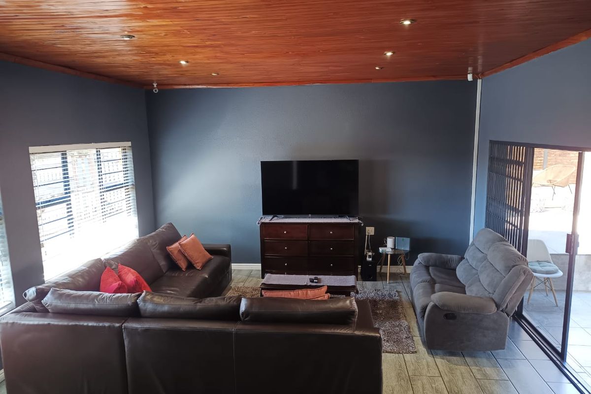 Spacious living room featuring a warm timber ceiling, recessed lighting, ceramic tiled flooring, and direct access to the outdoor area through sliding glass doors.