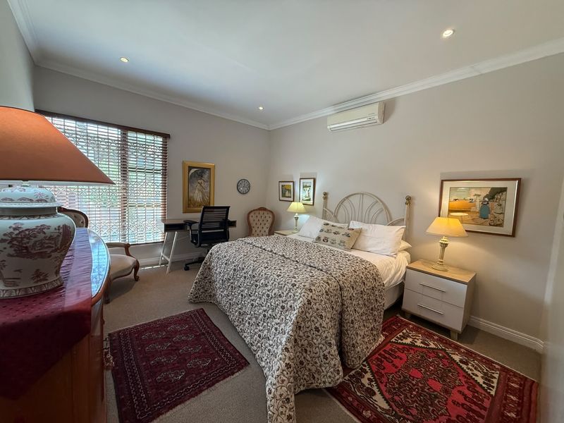 A well-maintained bedroom featuring recessed downlighting, a wall-mounted split-system air conditioner, and neutral wall finishes.
