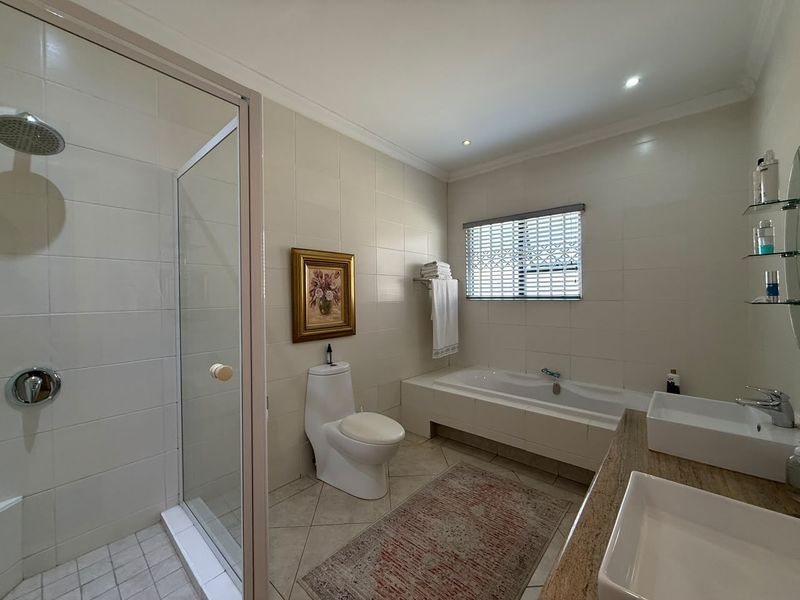 A well-maintained bathroom featuring a glass-enclosed shower, a built-in bathtub, and a double vanity with modern vessel sinks.