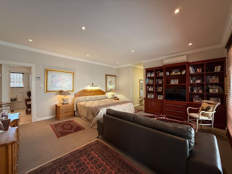 Spacious bedroom featuring built-in cabinetry, recessed downlighting, and an adjoining en-suite bathroom, offering a comfortable and well-maintained living space.