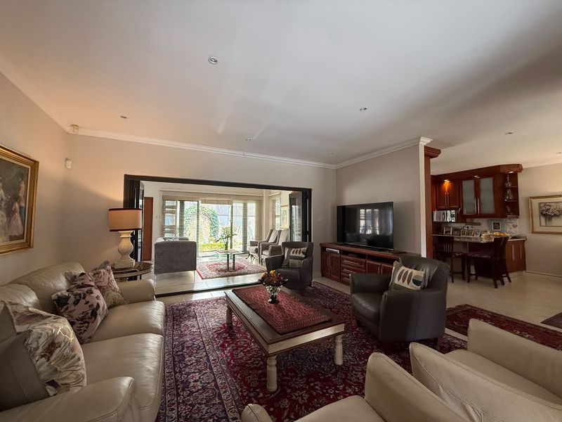 Spacious open-plan living area featuring tiled floors, recessed lighting, and seamless flow to an outdoor patio through large bi-fold doors.
