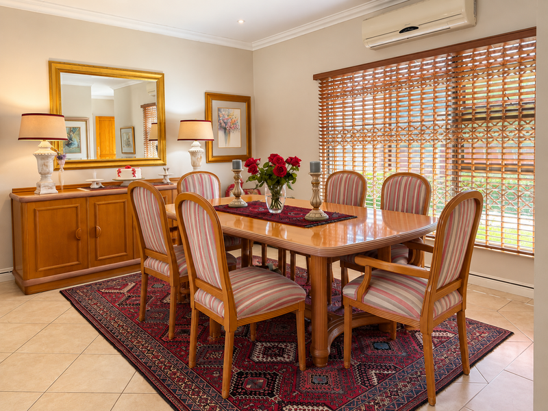 A well-maintained dining room featuring tiled flooring, cove cornicing, and a wall-mounted split-system air conditioner for climate control.
