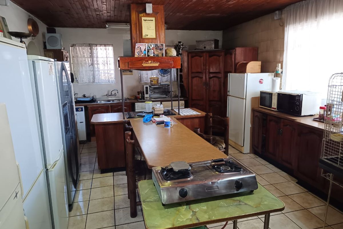Spacious kitchen featuring timber ceiling, tiled flooring, and extensive wooden cabinetry, offering a functional layout with potential for modern renovation.