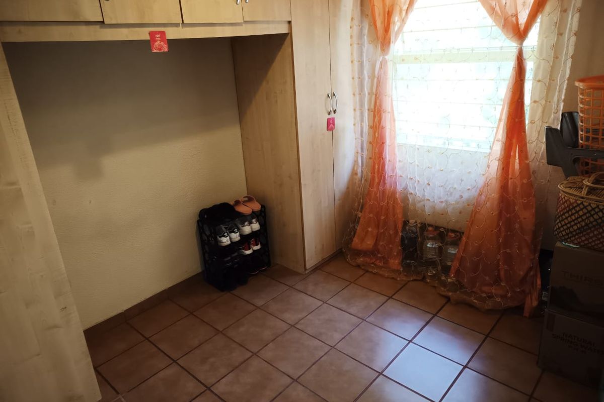 A bedroom featuring built-in cupboards and tiled flooring, providing functional storage space.