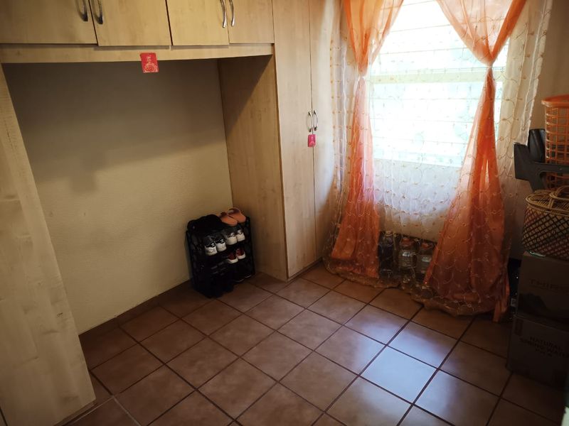 A bedroom featuring built-in cupboards and tiled flooring, providing functional storage space.