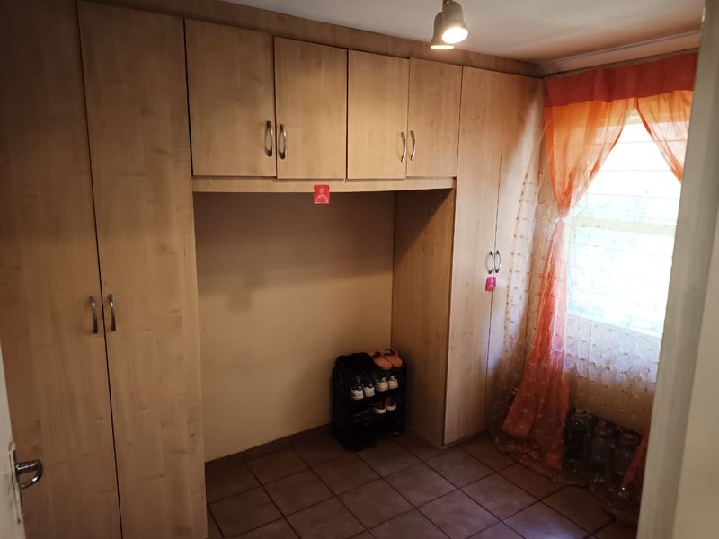 A bedroom featuring extensive built-in wooden cabinetry and tiled flooring, providing ample storage space and natural light through the window.
