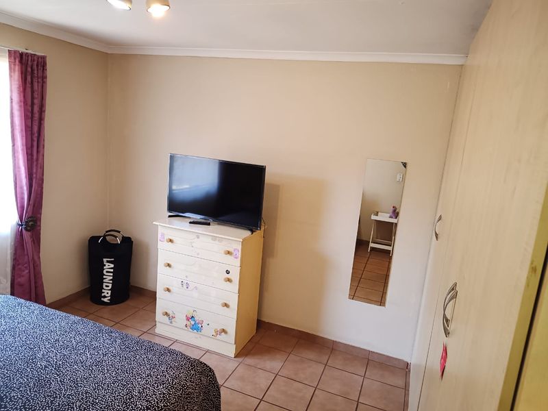 A bedroom featuring tiled flooring and a built-in wardrobe, providing functional storage space within the townhouse.