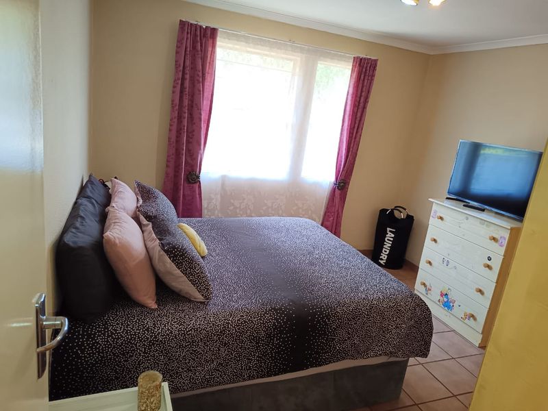 A standard bedroom featuring tiled flooring and a window with curtains, providing a functional space for rest.
