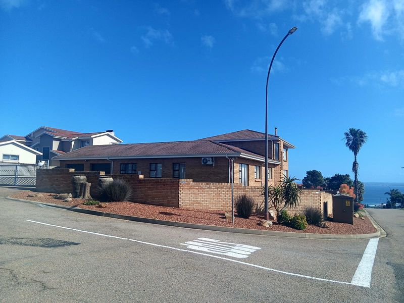 Street view of a brick-faced residential property featuring a tiled roof, perimeter boundary wall, and an external air conditioning unit.