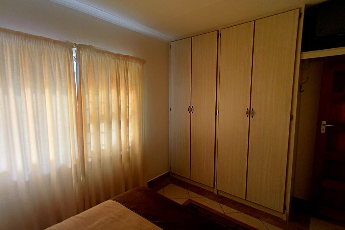 A bedroom featuring light wood-finish built-in cupboards and tiled flooring, providing functional storage space.
