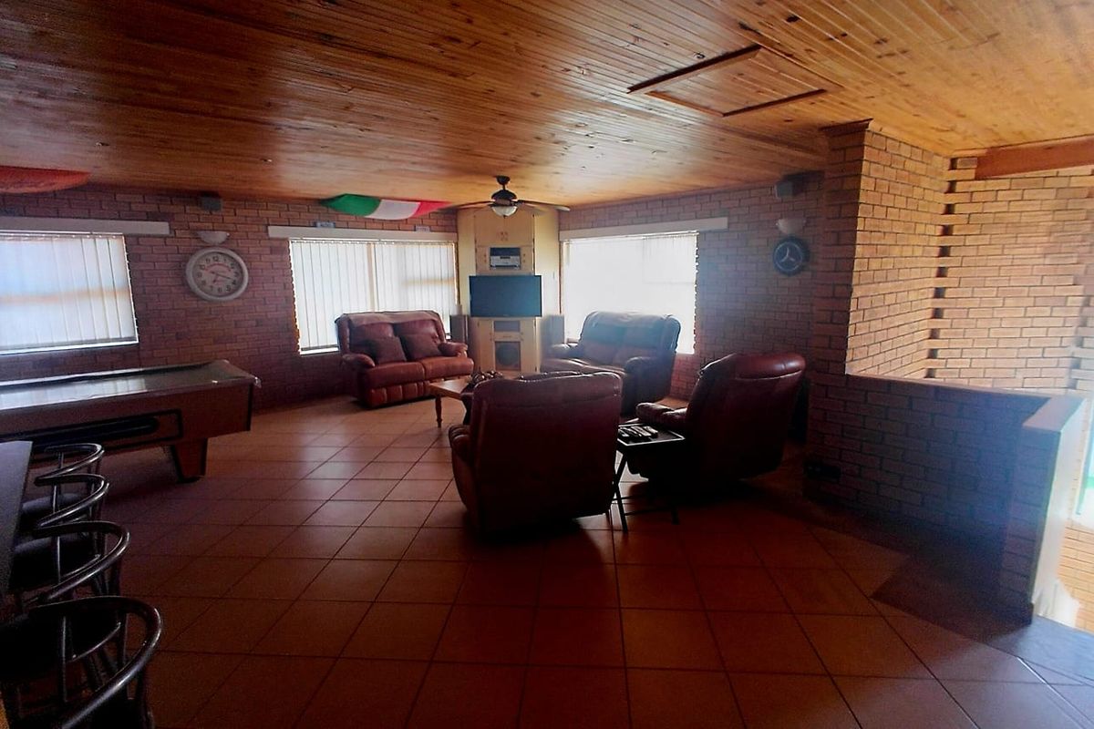 Spacious living area featuring exposed brick walls, a warm timber ceiling, and durable ceramic floor tiles, offering a rustic and comfortable atmosphere.