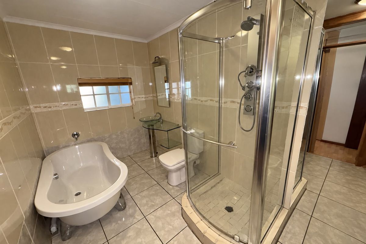 A functional bathroom featuring a freestanding bathtub, a separate glass-enclosed shower, and a glass vessel sink with neutral wall and floor tiling.