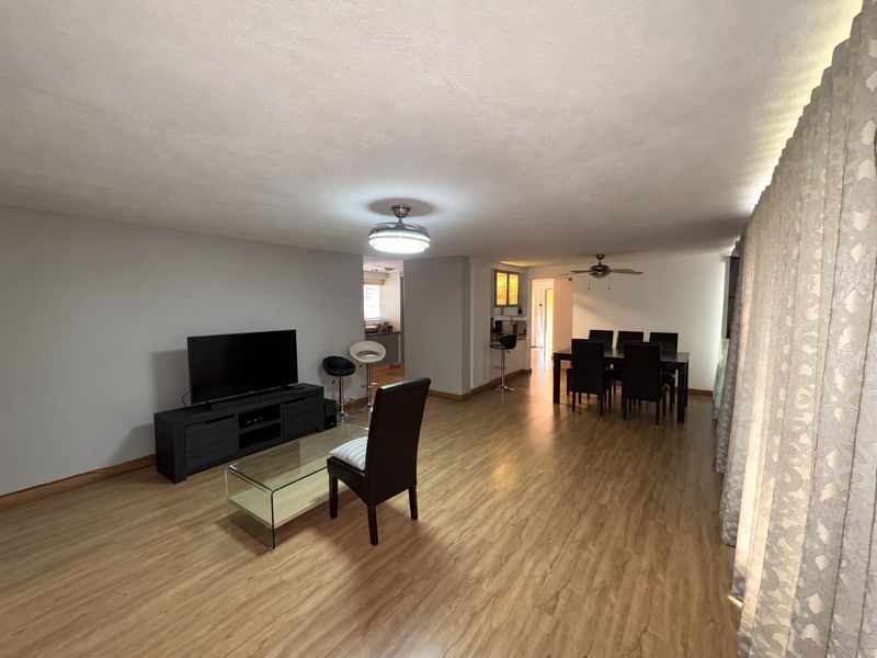 Spacious open-plan living and dining area featuring laminate flooring, ceiling fans, and neutral wall tones, providing a versatile layout for modern living.