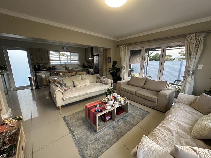 Spacious open-plan living area featuring tiled floors, integrated kitchen cabinetry, and large sliding glass doors providing access to the outdoor patio.