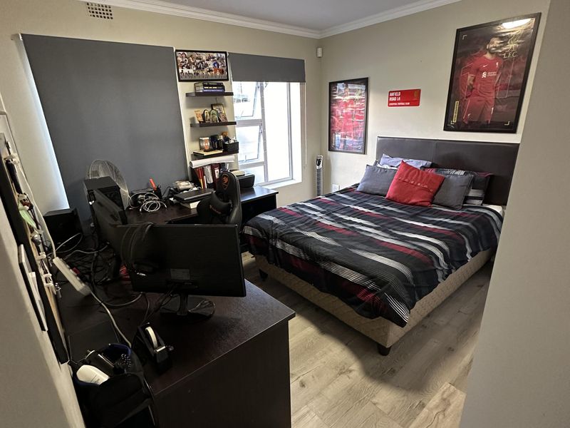 A functional bedroom featuring laminate flooring, built-in shelving, and a ceiling light fixture, providing a comfortable and practical living space.