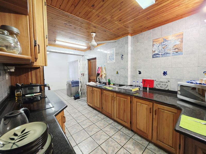 Functional kitchen featuring wooden cabinetry, granite countertops, a double sink, and a distinctive wooden tongue and groove ceiling.